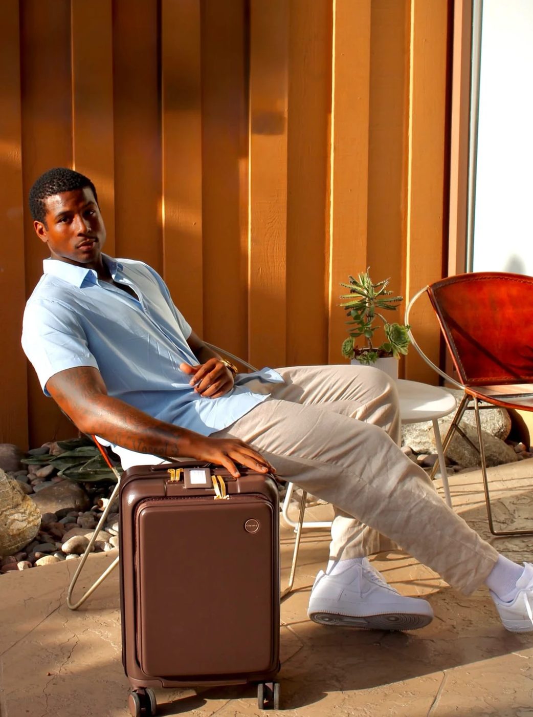 Model on a sunlit patio with carry-on luggage