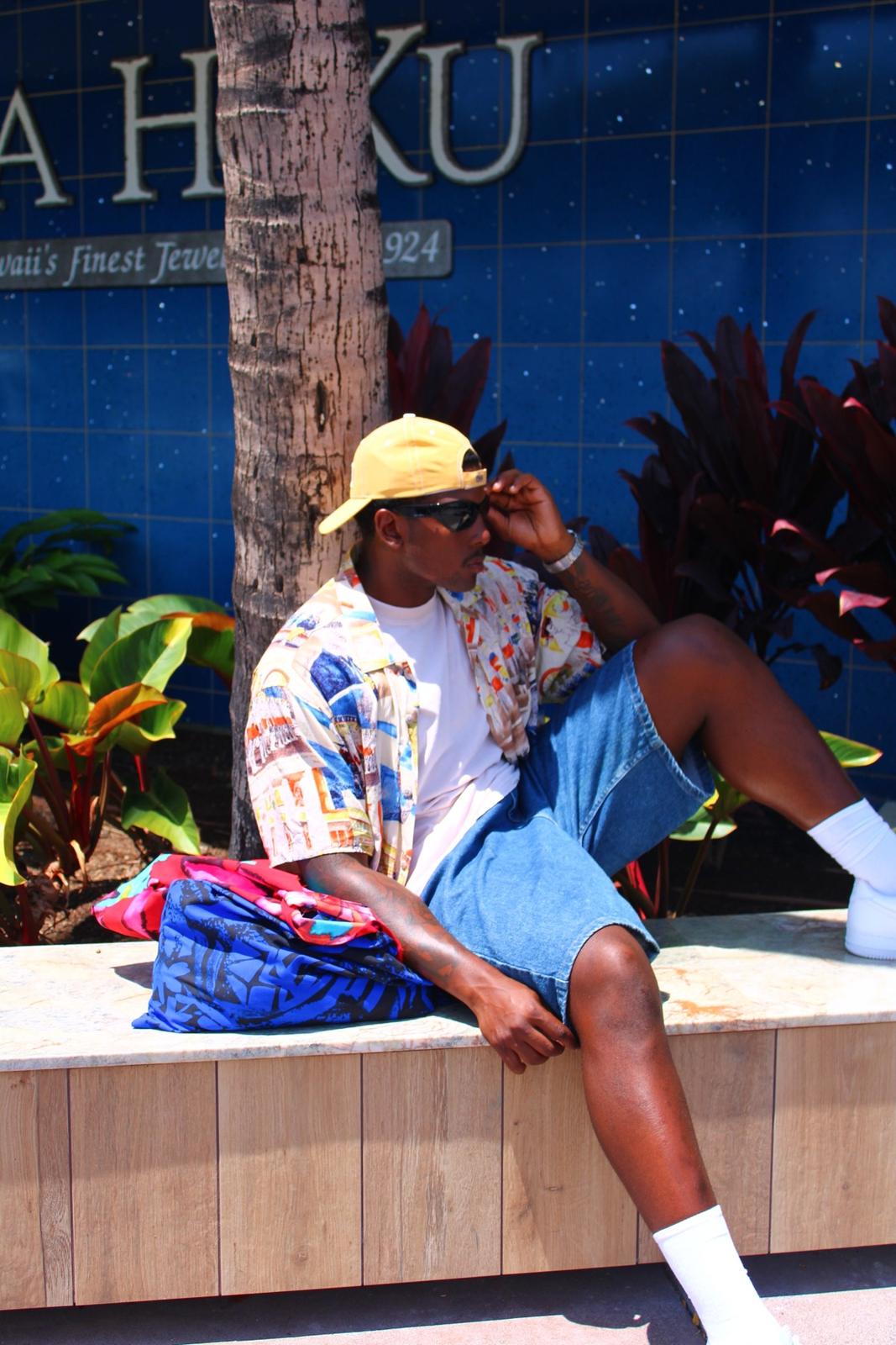 Model in a Jams World print shirt sitting outside a shop