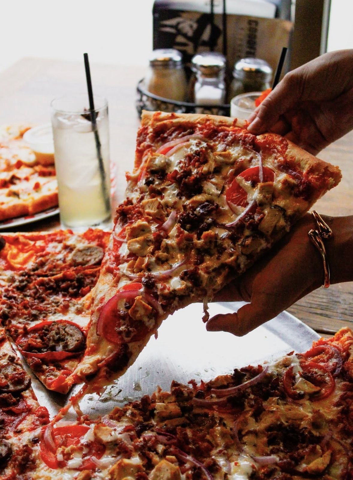 Hand pulling a loaded slice at Goodfellas Pizzeria, Indianapolis