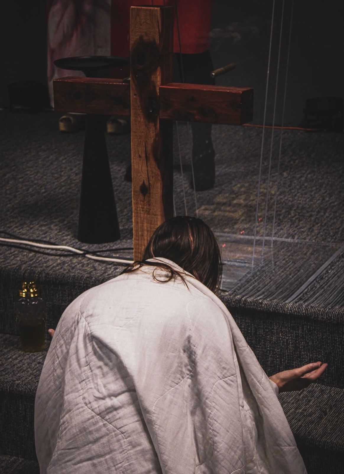 Worshipper kneeling at the foot of a wooden cross